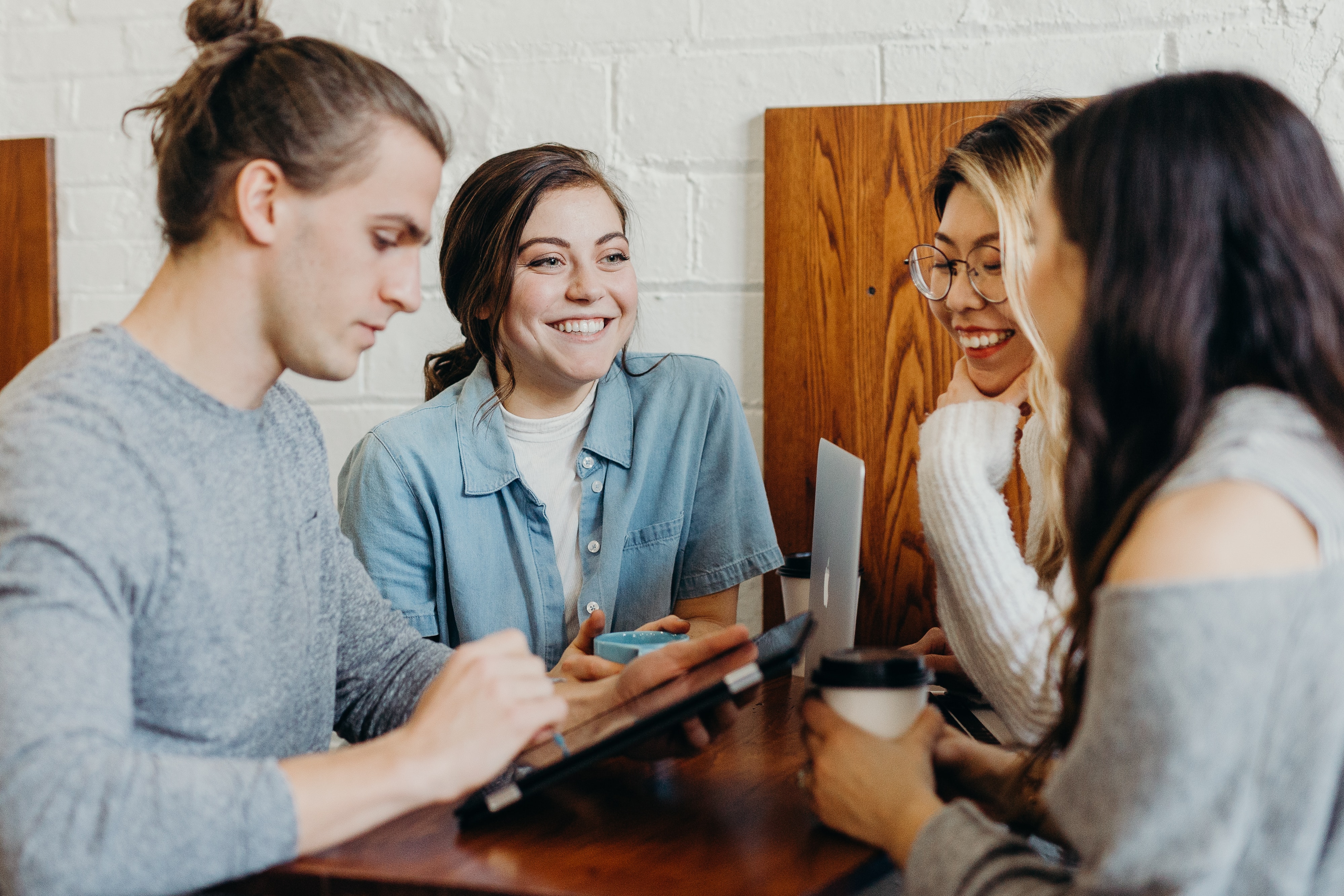 a group of college age student gathered around a table studying while drinking coffee